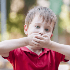 Child with autism covering his mouth with his hands