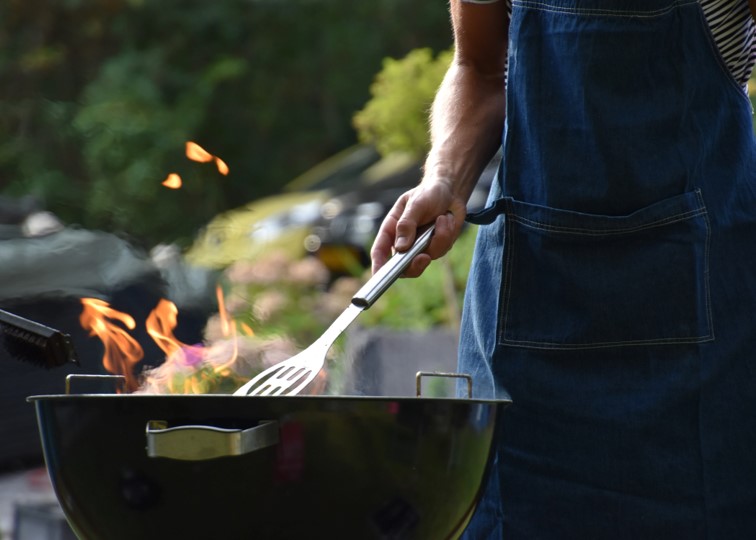 A person poking a BBQ with a spatula