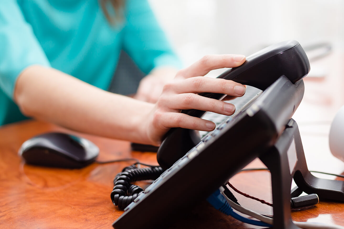 Woman in an office with her hand on a telephone