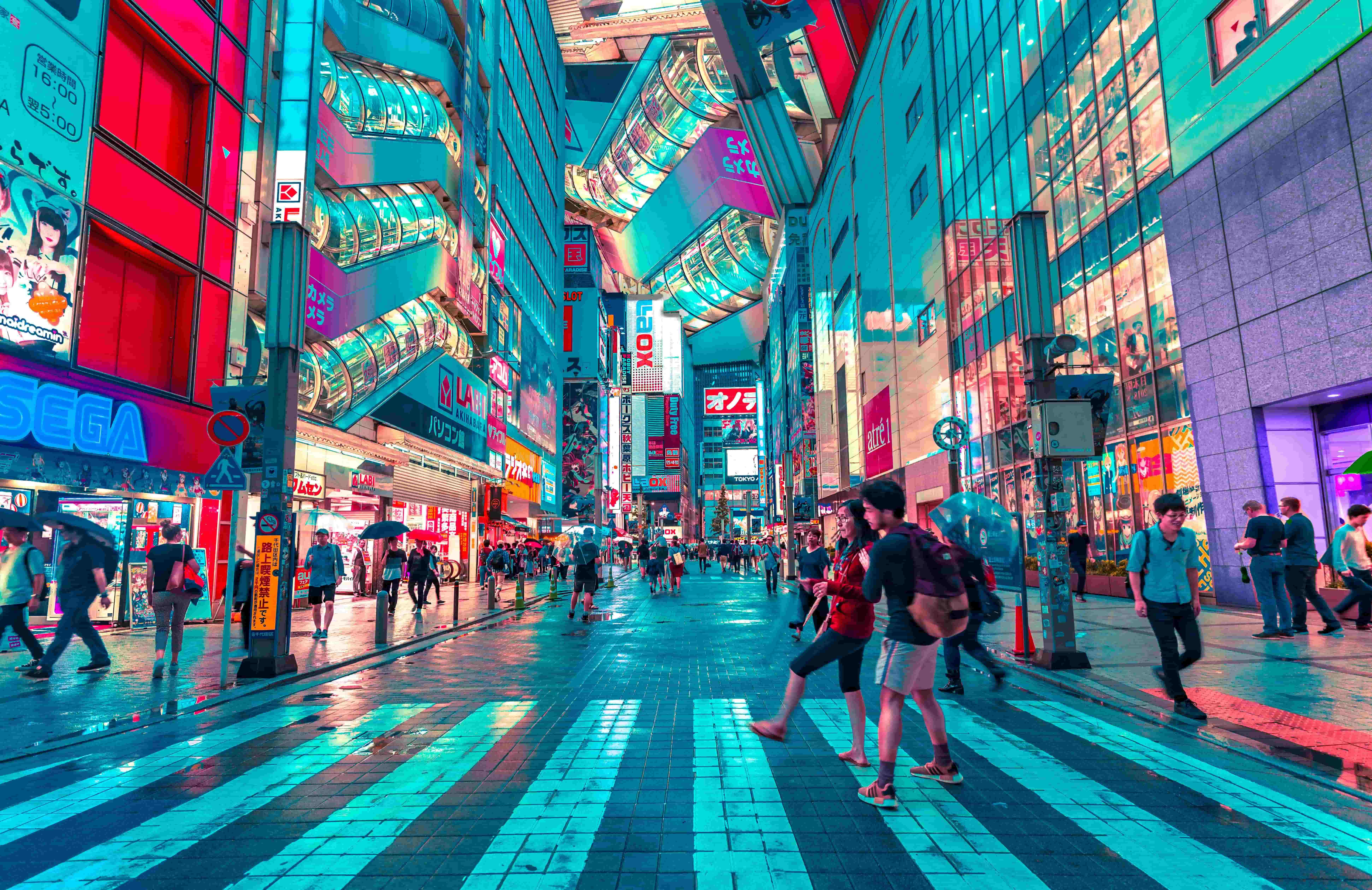 A couple crosses a zebra crossing in a Japanese City at night