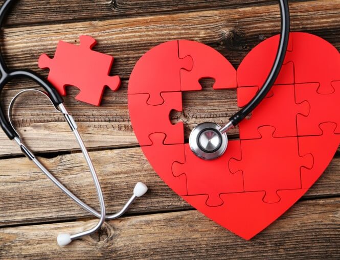 Red jigsaw puzzle heart under an adult Stethoscope