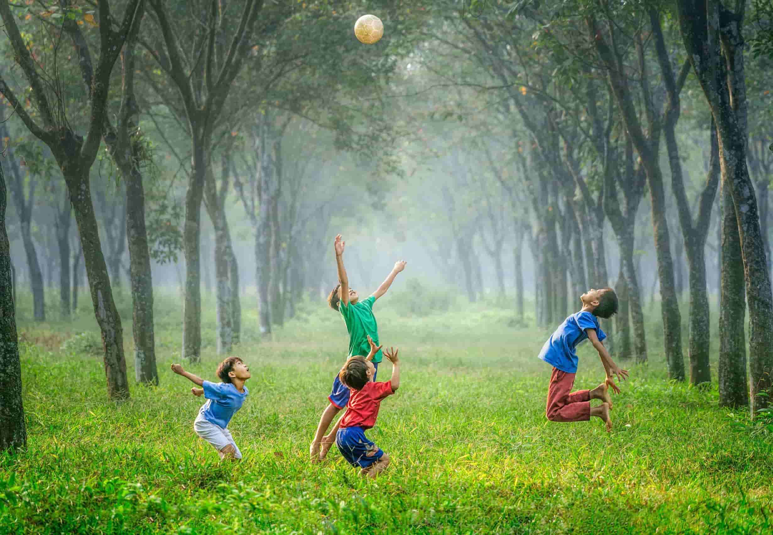 Four children jump in the air reaching for a ball